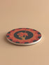 Round ceramic coaster featuring a skeleton hand holding a coral hibiscus flower, surrounded by art deco fan patterns in coral and black
