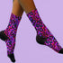 Coquette-style crew socks featuring a bold black background with hot pink and purple psychedelic squiggles, cherries, and shiny pink bows. Made of a soft polyester-spandex blend with reinforced black toe and heel. Fits US women's sizes 5–12 and men's up to 12. Stretchy, colorful, and cute for dopamine dressing.