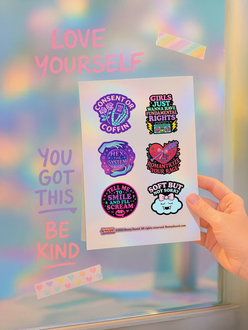 Feminist sticker sheet measuring 9.8x14 inches featuring 6 kiss-cut vinyl stickers with matte finish. Includes designs: “Consent or Coffin” (4.1x4), “Girls Just Wanna Have Fundamental Rights” (3.5x4.1), “Hex the System” (3.6x3.7), “Romanticize Your Rage” (3.7x3.3), “Tell Me to Smile and I’ll Scream” (3.6x3.6), and “Soft But Not Sorry” (~3.3"). Weather-resistant, semi-permanent adhesive, ideal for laptops, water bottles, and journals.