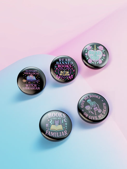 Five glossy 2.25-inch round pinback buttons with pastel punk book-themed designs. Each pin features a different bold phrase like “Read or Die,” “Books Are My Familiar,” and “Give Me Books or Give Me Death,” in pink, purple, and teal colors. Made of tinplate with a safety pin back and glossy scratch-resistant coating.