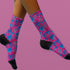 Fun and playful socks adorned with vibrant tiger head motifs on a pink background, with black heels and toes, ideal for animal lovers and those who enjoy unique designs