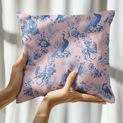 Luxury throw pillow cover featuring a gothic toile pattern in deep blue on a soft pink background, with skeletal figures, peacocks, and floral motifs.