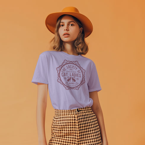 The Society of Childless Cat Ladies Against Couch Fuckers" 2024 election T Shrort design featuring two cats in an ornate circular frame, available in white and purple.