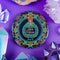 Circular pinback button featuring an ornate teal poison bottle labeled "Aqua Tofana" on black background, framed by decorative coral and turquoise flowers. Gothic feminist history pin with glossy finish and safety pin backing, available in 2" and 3" sizes for witch aesthetic fashion.