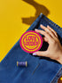 A round, 3-inch embroidered Love Louder patch designed with a vibrant, retro 70s aesthetic. The design features groovy, puffy-style text in a bright, sunny yellow thread, set against a bold magenta pink twill fabric background. The words 'LOVE LOUDER' are stacked to fill the center, encircled by concentric yellow rings that create a hypnotic, radiating effect. The entire circular patch is finished with a clean, durable merrowed border.