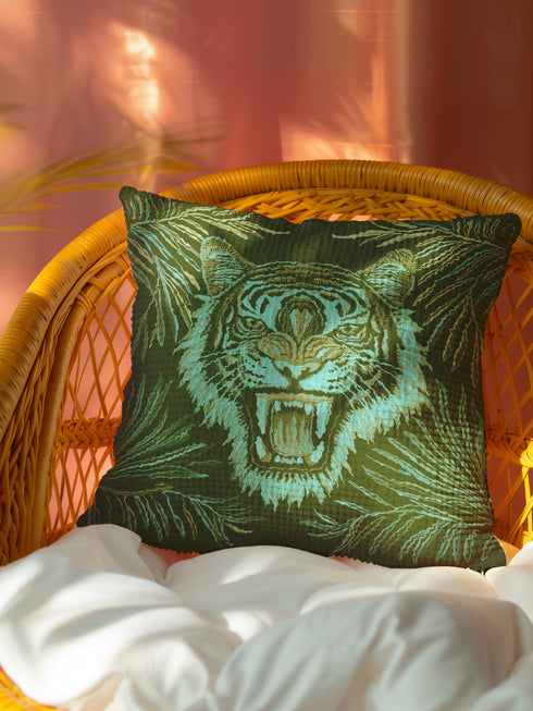 Square woven pillow featuring fierce turquoise tiger with bared fangs against olive green background surrounded by jungle leaves. Textured tapestry creates vibrant mid-century tiki decor perfect for rockabilly, maximalist room styling.