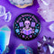 Literary rebel's badge of honor. Black circular button featuring a neon purple skeleton surrounded by floating books and stars. The text 'READ BANNED BOOKS' arcs across the top in bold purple lettering. Perfect for book-loving misfits who devour forbidden knowledge.