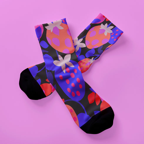 Black crew socks featuring an oversized, abstract strawberry pattern in bright pink, blue, and orange.