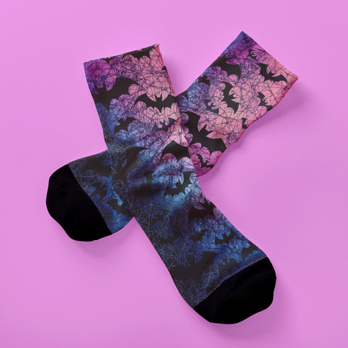 Black crew socks featuring an ombre pink-to-blue gradient with silhouetted bats and spiderweb details.
