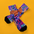 Stylish jungle-themed socks with tigers and abstract camo patterns in a palette of purple, blue, and pink, laid out on a yellow background, ideal for adding a pop of color to your wardrobe