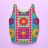 A high-resolution product photo of a body-hugging, 2D printed crop top with a 1970s-inspired floral patchwork pattern. The design consists of vibrant squares in cobalt blue, pale lavender, and deep violet, separated by pink borders with red dots. Central motifs include yellow daisies with orange centers and green-magenta floral mandalas. The top is made of a smooth, high-stretch performance knit fabric with curved back armholes and a cropped waistline.