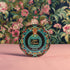 Circular pinback button featuring an ornate teal poison bottle labeled "Aqua Tofana" on black background, framed by decorative coral and turquoise flowers. Gothic feminist history pin with glossy finish and safety pin backing, available in 2" and 3" sizes for witch aesthetic fashion.