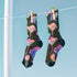 Black crew socks with an allover design of iridescent neon mushrooms in shades of pink, blue, and purple.