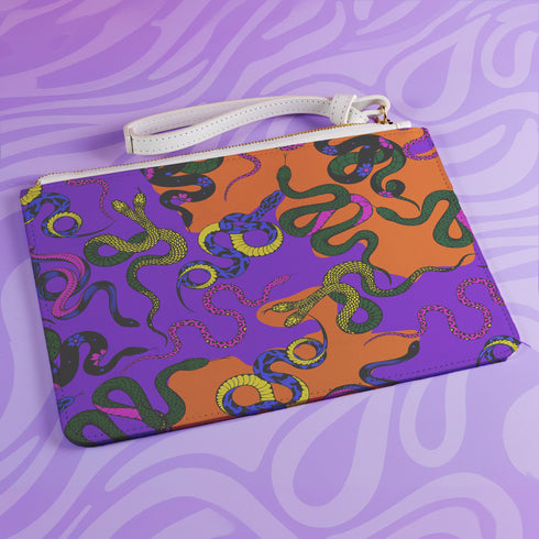 Rectangular wristlet clutch featuring vibrant purple and orange background with colorful snake prints. White strap and gold zipper visible.