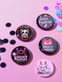 A set of five glossy round pinback buttons with pastel goth and kawaii punk designs, featuring slogans like "Eat The Rich" and "Smash Fascism" in bold pink and black. Each pin has a cute character delivering a powerful message.