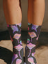 Black crew socks with an allover design of iridescent neon mushrooms in shades of pink, blue, and purple.