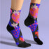 Black crew socks featuring an oversized, abstract strawberry pattern in bright pink, blue, and orange.