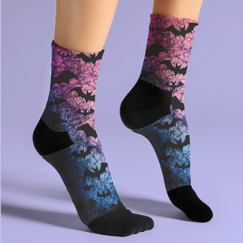 Black crew socks featuring an ombre pink-to-blue gradient with silhouetted bats and spiderweb details.