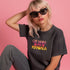 Faded vintage Black t-shirt with "Cat Ladies for Kamala" in retro-style pink and yellow lettering. Cat silhouettes accent the text.