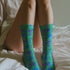 Fun and playful socks adorned with vibrant tiger head motifs on a green background, with black heels and toes, ideal for animal lovers and those who enjoy unique designs