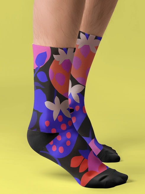 Black crew socks featuring an oversized, abstract strawberry pattern in bright pink, blue, and orange.
