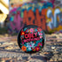 A black round pinback button featuring floral embroidery-style designs and bold red text that reads "Obey Nothing."