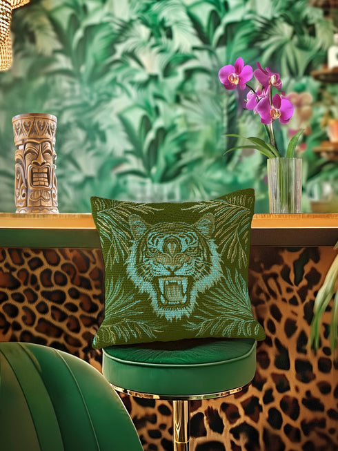 Square woven pillow featuring fierce turquoise tiger with bared fangs against olive green background surrounded by jungle leaves. Textured tapestry creates vibrant mid-century tiki decor perfect for rockabilly, maximalist room styling.