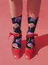 Black crew socks with an allover design of iridescent neon mushrooms in shades of pink, blue, and purple.