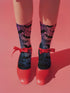 Black crew socks featuring an ombre pink-to-blue gradient with silhouetted bats and spiderweb details.