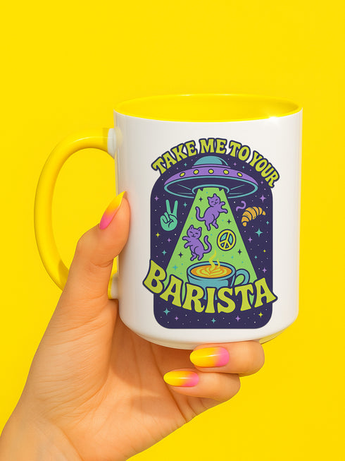 White ceramic coffee mug with a bright yellow handle and interior, featuring a printed alien abduction design with two purple cats, peace signs, and the phrase “Take Me to Your Barista” in green and purple text.