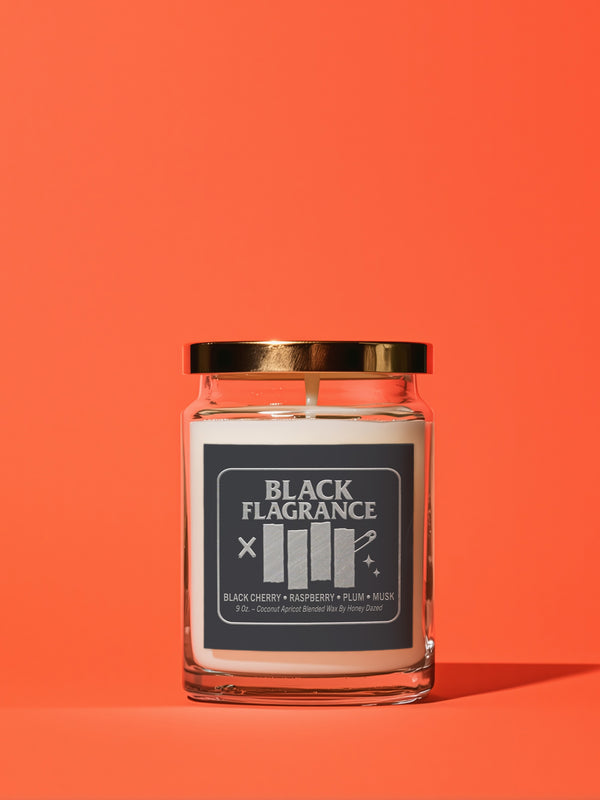 A 9-ounce hand-poured candle in a clear, cylindrical glass jar with a slight taper at the base. The wax is a creamy, solid off-white color, filling the jar to just below the rim where a single white cotton wick is centered. The label features the words "BLACK FLAGRANCE" in a bold, white, sans-serif font. Below this, a stylized graphic mimics a famous punk band logo with four vertical white bars. The candle is topped with a shiny, metallic gold-colored lid.
