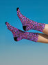 Coquette-style crew socks featuring a bold black background with hot pink and purple psychedelic squiggles, cherries, and shiny pink bows. Made of a soft polyester-spandex blend with reinforced black toe and heel. Fits US women's sizes 5–12 and men's up to 12. Stretchy, colorful, and cute for dopamine dressing.