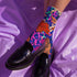Stylish jungle-themed socks with tigers and abstract camo patterns in a palette of purple, blue, and pink, laid out on a yellow background, ideal for adding a pop of color to your wardrobe