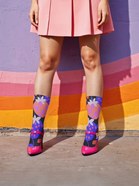 Black crew socks featuring an oversized, abstract strawberry pattern in bright pink, blue, and orange.