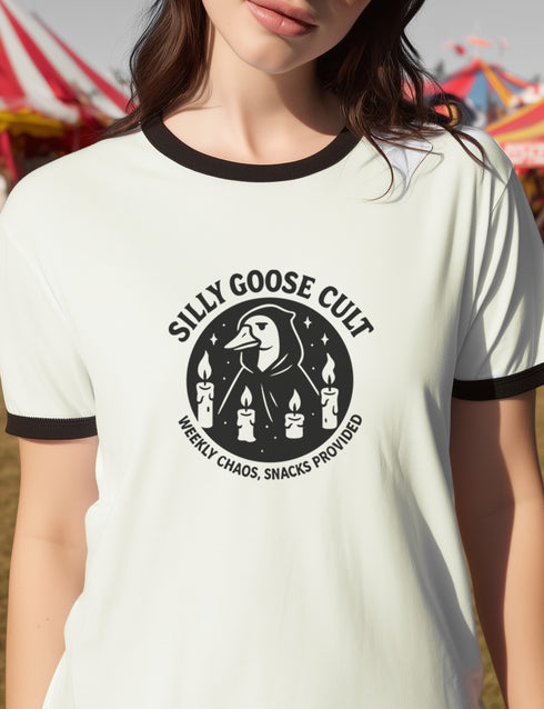 Unisex ringer t-shirt in natural cotton with black ribbed collar and sleeve cuffs. Front features bold black graphic: a cult-style goose surrounded by four candles, with text reading “Silly Goose Cult, Weekly Chaos, Snacks Provided.” Available in sizes S to 3XL. Retro-inspired fit, soft cotton, statement weirdcore design for alternative fashion lovers.