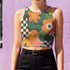 Cropped racerback tank top featuring bold retro floral print with orange and yellow mod flowers, green leaves, black and white checkerboard pattern, and abstract wavy designs. Fitted athletic style crop top in vibrant 70s inspired botanical print with performance fabric construction. Women's festival rave wear cropped camisole with psychedelic flower power design perfect for summer concerts, Y2K fashion looks, and alternative streetwear styling.