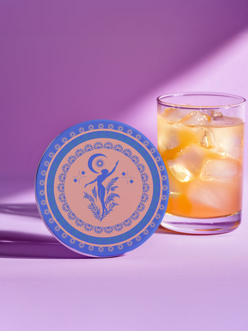 Round ceramic coaster featuring a silhouetted dancing figure reaching toward a crescent moon, surrounded by concentric rings of stars and floral patterns in blue on peach background