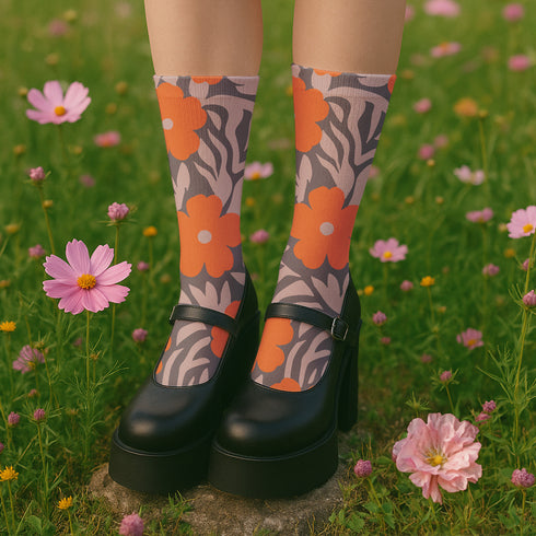 Colorful mid-calf crew socks featuring a bold orange hibiscus floral pattern layered over wavy zebra stripes in taupe and gray, with black heels and toes.