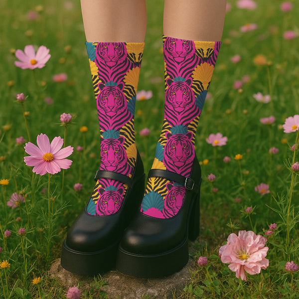 Colorful pink tiger print crew socks with black heel and toe, featuring yellow zebra stripes and teal and coral fan-shaped accents. Made of stretchy knit with a bold maximalist aesthetic. One size fits most, mid-calf length, vibrant all-over print