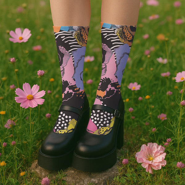Colorful crew-length socks with a vibrant floral pop-art collage design, featuring abstract roses in yellow, lavender, pink, and orange tones, polka dots, and zebra stripes on a black background.