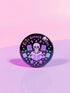 Literary rebel's badge of honor. Black circular button featuring a neon purple skeleton surrounded by floating books and stars. The text 'READ BANNED BOOKS' arcs across the top in bold purple lettering. Perfect for book-loving misfits who devour forbidden knowledge.