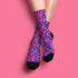 Coquette-style crew socks featuring a bold black background with hot pink and purple psychedelic squiggles, cherries, and shiny pink bows. Made of a soft polyester-spandex blend with reinforced black toe and heel. Fits US women's sizes 5–12 and men's up to 12. Stretchy, colorful, and cute for dopamine dressing.