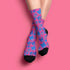 Fun and playful socks adorned with vibrant tiger head motifs on a pink background, with black heels and toes, ideal for animal lovers and those who enjoy unique designs