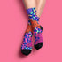 Stylish jungle-themed socks with tigers and abstract camo patterns in a palette of purple, blue, and pink, laid out on a yellow background, ideal for adding a pop of color to your wardrobe