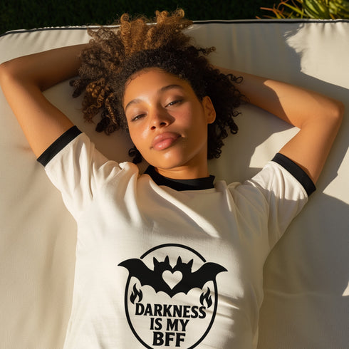 Unisex off-white and black ringer t-shirt with black bat and heart graphic and the phrase "Darkness Is My BFF" in bold gothic style, contrasting black ribbed collar and cuffs, vintage-inspired, available in sizes S-3XL, soft 100% cotton, alternative fashion, perfect goth gift.