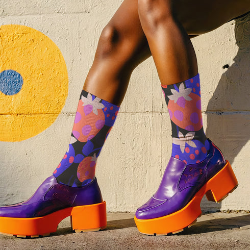 Black crew socks featuring an oversized, abstract strawberry pattern in bright pink, blue, and orange.