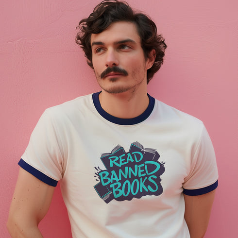 Off-white ringer t-shirt with navy contrast trim on the collar and sleeve cuffs. The front features a bold graffiti-style graphic with the phrase "READ BANNED BOOKS" in vibrant turquoise, layered over a stack of illustrated books in dark navy and black. The hand-drawn lettering and ink-splatter details give the design a rebellious, street-art-inspired aesthetic. The t-shirt has a vintage-inspired fit, made from soft cotton fabric with a slightly relaxed silhouette. The navy trim complements the graphic, add