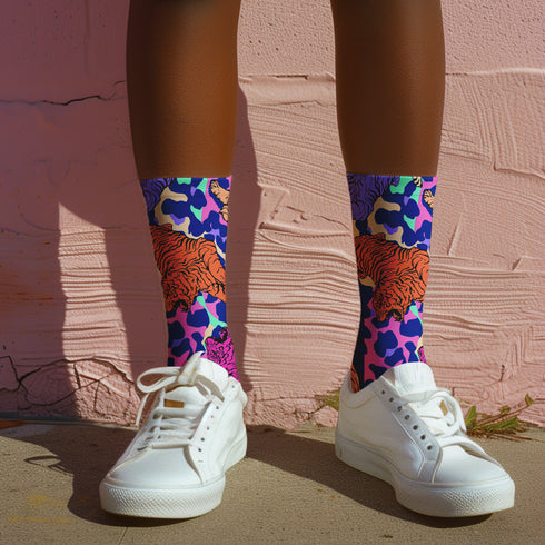 Stylish jungle-themed socks with tigers and abstract camo patterns in a palette of purple, blue, and pink, laid out on a yellow background, ideal for adding a pop of color to your wardrobe