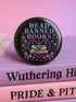 Glossy black pinback button that says “Read Banned Books” in purple and teal letters, featuring a chained book, roses, bows, and floral accents, styled on colorful books and pastel backgrounds.