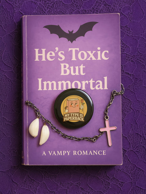 A glossy black round pin-back button with a retro 1970s-style design. The center shows a smiling cartoon paperback book holding a red rose, colored light brown with white gloves and feet. Below, “MY TYPE IS PAPERBACK” appears in chunky brown-and-tan 70s lettering. This bookish flair piece has a high-gloss, scratch-resistant mylar finish, secure safety pin backing, and comes in two- or three-inch sizes.